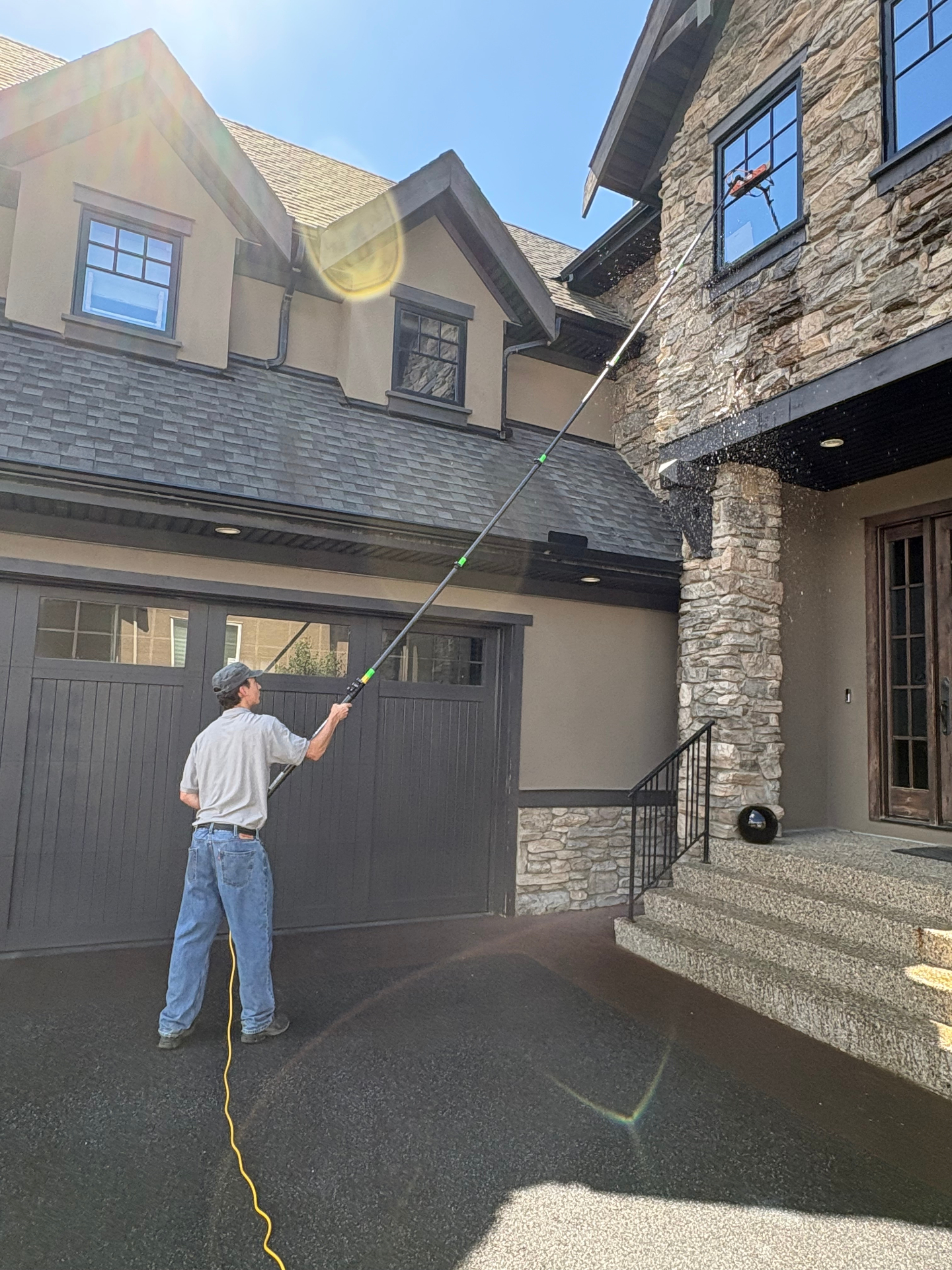 Water-fed pole cleaning high windows on a stone home